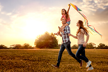 Father, mother and daughter running with a kite outside